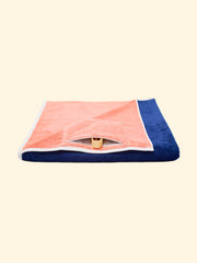 Modelo "Konoh" de la toalla de playa de marca Tucca, doblada mostrando el bolsillo oculto impermeable con cierre de cremallera, que puede ser usado para guardar tu teléfono u otras pertenencias, así como para guardar tus pinzas Tucca después de usarlas para fijar tu toalla de playa a la arena.                                