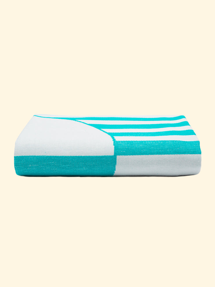 Modelo "Mayeri" de Tucca toalla de playa ligera 100% algodón orgánico, perfectamente doblado como se presenta en el envase. Mostrando que es una cosa muy toalla de playa fácil de llevar.