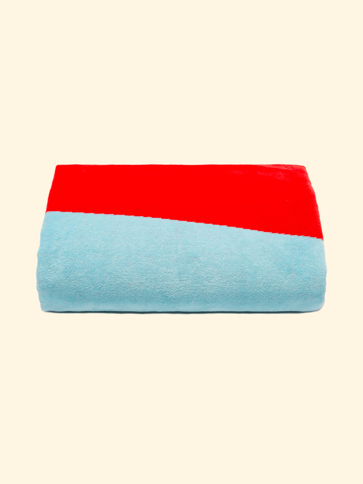 Modelo "Berry" de toalla de playa Tucca perfectamente plegada como se presenta en el embalaje, con dos pinzas tucca a cada lado, que se pueden utilizar para fijar tu toalla de playa a la arena.                                