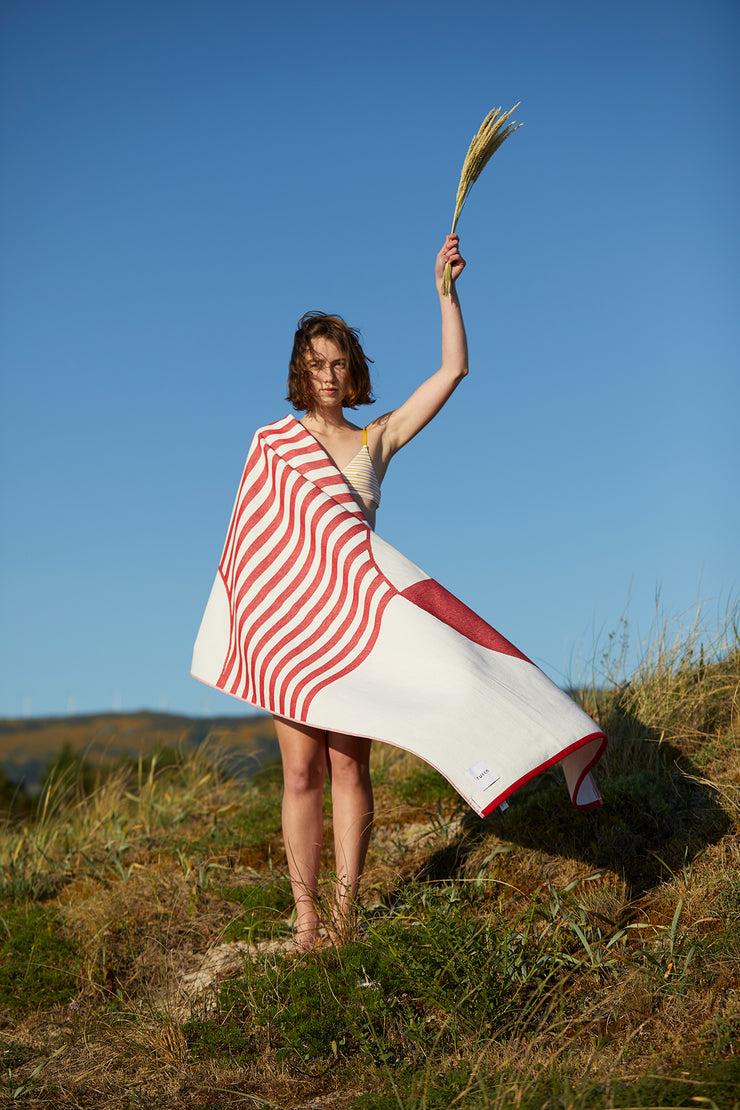 Girl covering herself with the Tucca "Crassa" style. An extra light beach towel that doesn't get blown by the wind. Super soft texture as it is made with 100% organic cotton.